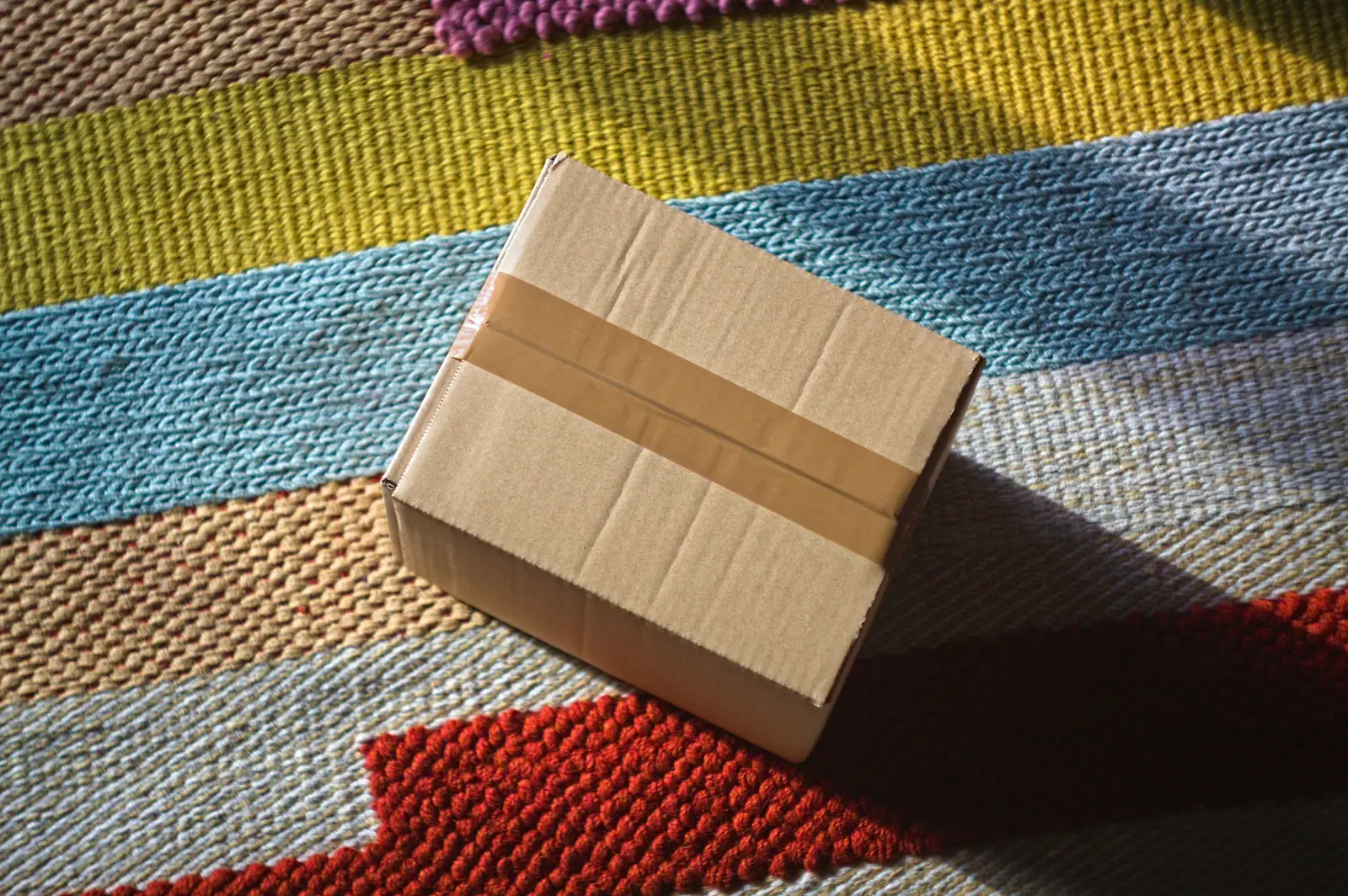 Colis en carton posé sur un tapis coloré