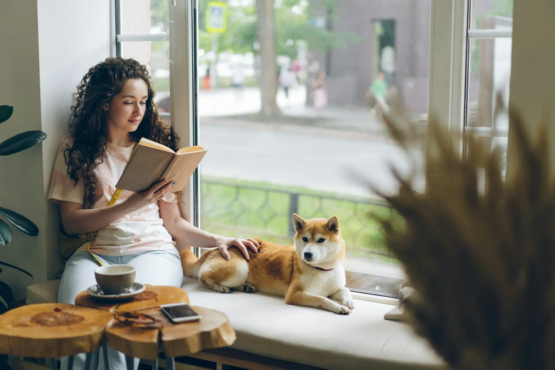 Femme qui lit sur le rebord d’une fenêtre, son chien à côté d’elle