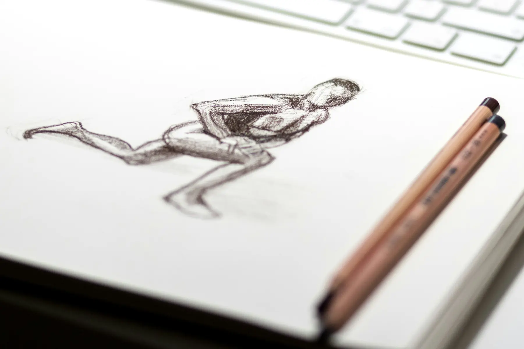 Croquis au crayon dans un carnet, à côté du clavier
