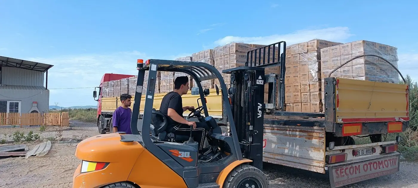 Chariot élévateur qui charge des briques sur un camion